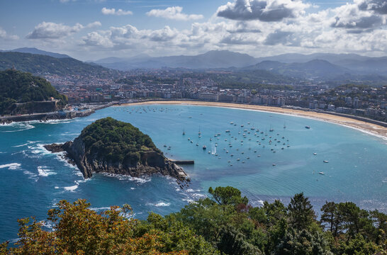 Vista panor&aacute;mica elevada de la bah&iacute;a de La Concha en San Sebasti&aacute;n, destacando la Isla de Santa Clara, los barcos fondeados y las monta&ntilde;as al fondo.