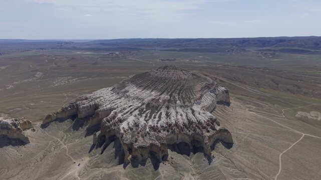 Aerial view of the eroded white limestone cliffs of Sherkala mountain surrounded by the vast arid desert landscape of Aktau, Mangystau Region, Kazakhstan.