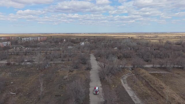 Aerial view of the abandoned Semipalatinsk Nuclear Test Site with decaying buildings and a vehicle on a desolate road in Semey, Abai Region, Kazakhstan.