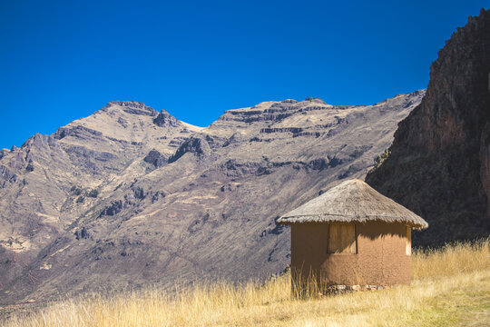 View of a traditional round hut with a thatched roof situated in the mountainous landscape of the Sacred Valley in Urubamba Province, Cusco, Peru.
