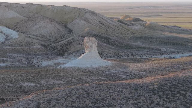 Aerial view of the striking white limestone rock formation at Tuzbair salt flat, surrounded by arid desert landscape under soft light in Kizyl-Bas, Mangystau Region, Kazakhstan.