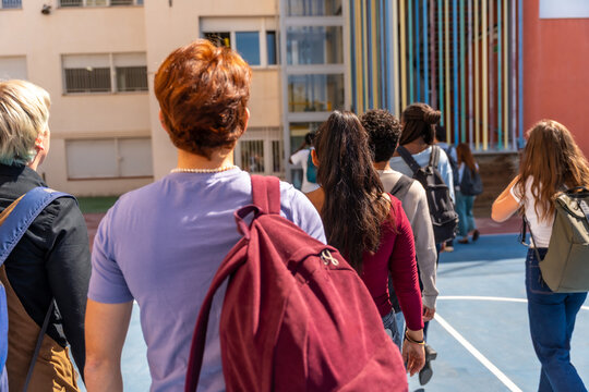 Diverse students walking with backpacks entering school campus