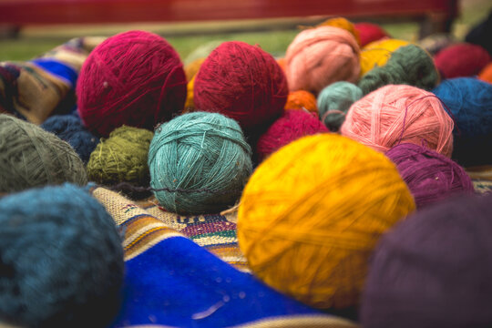View of colorful balls of yarn dyed with natural pigments, arranged on a traditional textile in Cusco, Cusco, Peru.