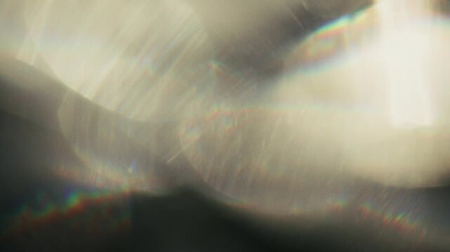 Light leak caustic abstract lens effect background with defocused flare and glare flickers from sunlight refraction with bokeh shimmer radiant illumination on dark.