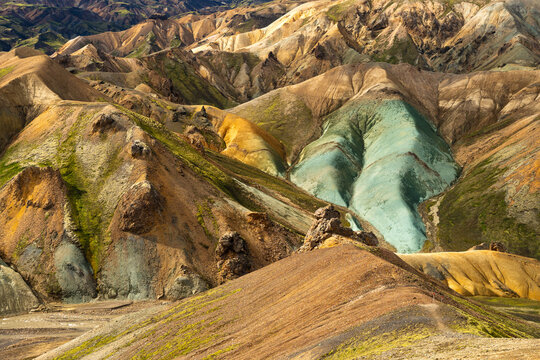 View of Landmannalaugar featuring colorful rhyolite mountains with patches of green moss and volcanic terrain in Rangarthing ytra, Iceland.