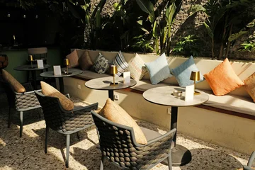 Fotobehang Horeca Elegant restaurant lounge with comfortable seating, warm table lamps, tropical plants, and stylish interiors.  © Yuliya