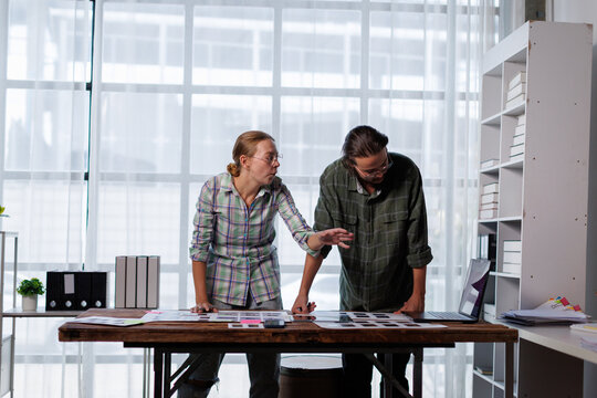 Creative professional team collaborating on design project, reviewing color palettes and visual concepts for a new product, working together in a modern office space