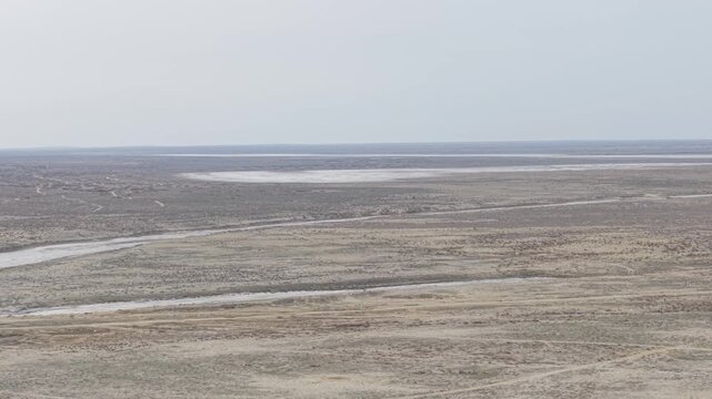 Aerial view of the arid Aral Sea landscape with dry lake bed and sparse vegetation in Aral, Kyzylorda Region, Kazakhstan.