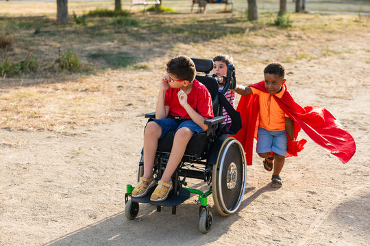 Diverse kids playing, pushing, running with wheelchair