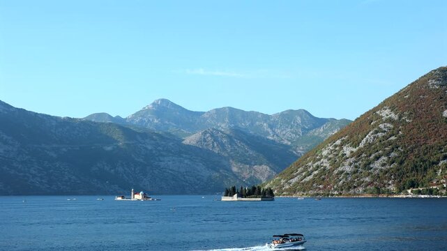 Adriatic Bay with Island Church and Mountains. Scenic Adriatic bay with island churches, blue sea, mountains and a tourist boat on a sunny day.