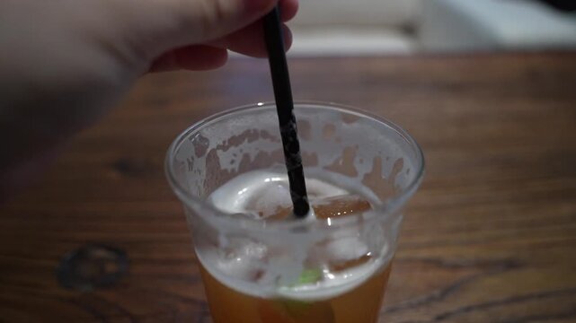 Close up. Someone stirring an iced drink before drinking.