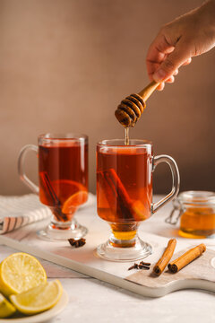 Honey poured into aromatic tea with cinnamon and citrus