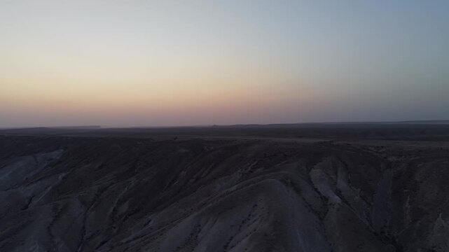 Aerial view of the vast desert landscape at sunset with rolling hills and rocky terrain in Mangistau, Mangystau Region, Kazakhstan.