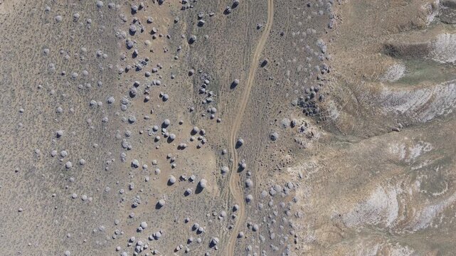 Aerial view of the spherical rock formations in the Torysh Valley, with a dirt road winding through the desert landscape in Aktau, Mangystau Region, Kazakhstan.