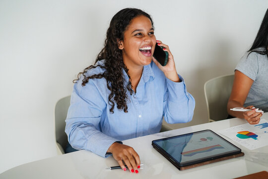 African american young business woman smiling on camera while calling a colleague inside corporate office - Female entrepreneurs and job concept - Focus on face