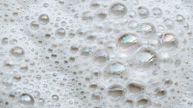 Close-up of white soap suds with iridescent bubbles and foam texture