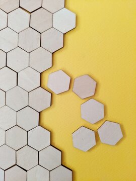 honeycomb seamless pattern. A flat lay composition of wooden hexagon tiles arranged in a honeycomb pattern on a bright yellow background with several detached pieces.