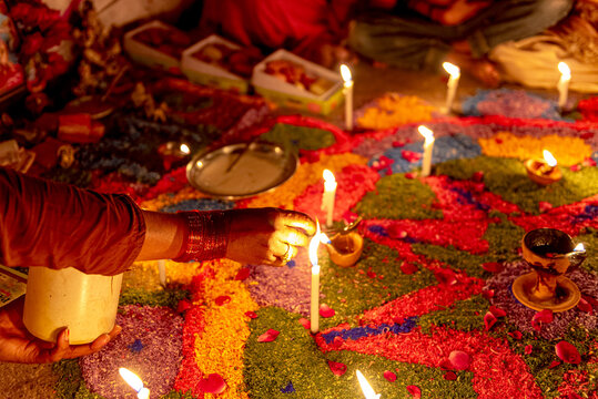 View of a person lighting diyas on a colorful rangoli pattern during the Diwali festival in Rahim Yar Khan, Punjab, Pakistan.