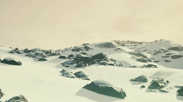 Snow covers a wide area with scattered rocks. The sky has clouds that block sunlight. This scene is from a remote location, likely in winter.