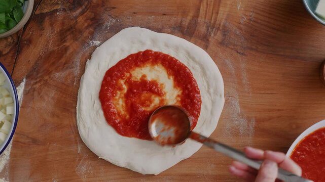 Pizza making, putting sauce san Marzano on sourdough pizza base
