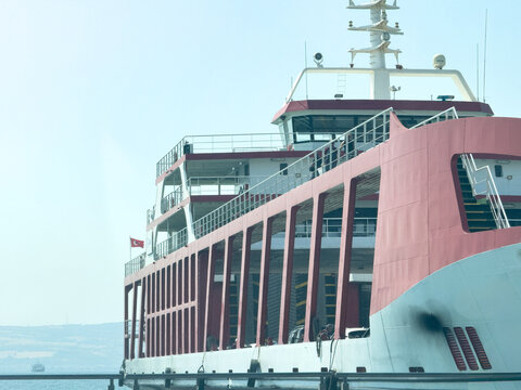 View of a large red and white ferry boat navigating the Dardanelles strait with the coastline visible in the background in Canakkale, Canakkale, Turkiye.