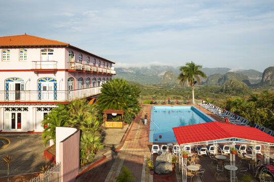 View of the swimming pool at Hotel Los Jazmines with the Vinales Valley and mogotes in the background under a clear blue sky in Vinales, Pinar del Rio, Cuba.
