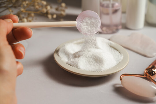 Collagen powder in scoop above supplement powder, close up beauty and wellness concept