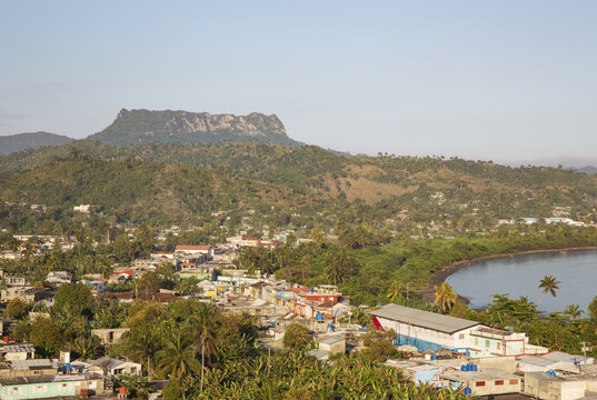 View of the coastal town of Baracoa with the iconic El Yunque mountain rising in the background, surrounded by lush tropical vegetation and palm trees in Baracoa, Guantanamo, Cuba.