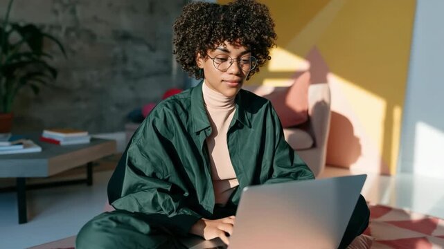Young person with curly hair using laptop in bright modern studio for remote work background and poster banner design