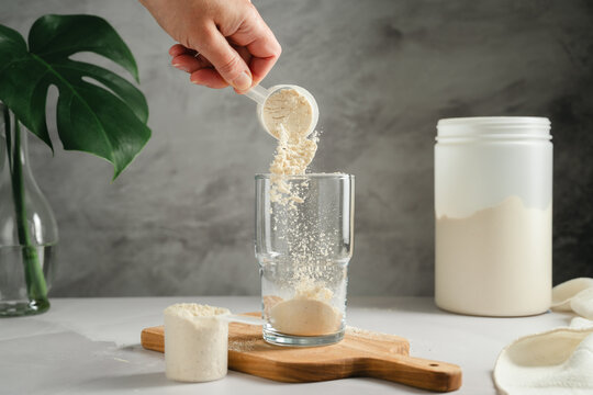 Protein powder being poured into glass, sports nutrition concept
