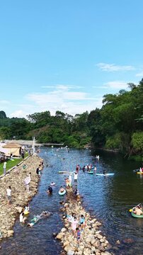 Vertical Video: Lively summer festival vibe by the karst river with tents and swimmers everywhere