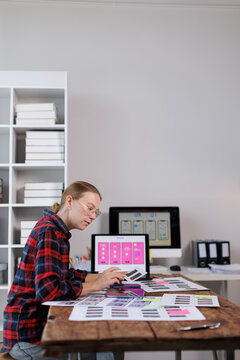 Woman ux designer working on mobile application user interface layout, creating wireframes and app prototypes on a computer at a creative office desk