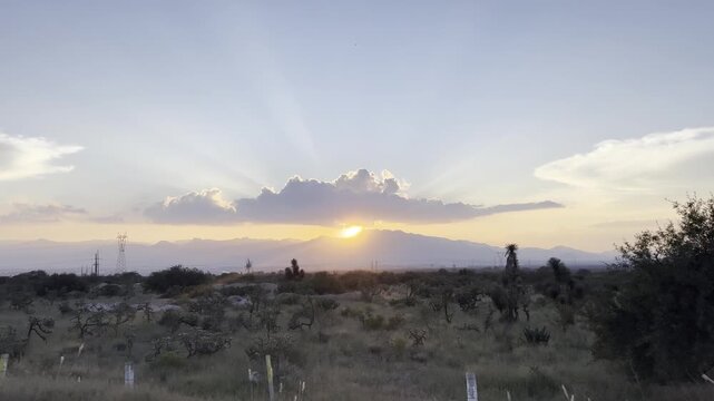 Wide view of the valley with low sun near the cross, expressing Christian hope and saving love.