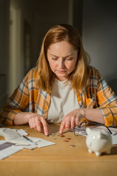 Cost of living crisis concept with worried woman counting coins at home