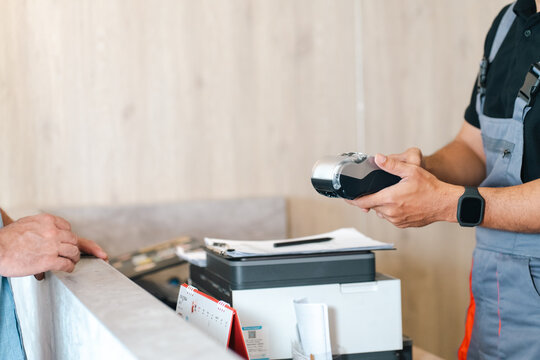 Electric vehicle battery car service delivery worker uses handheld scanner beside printer and package at service counter
