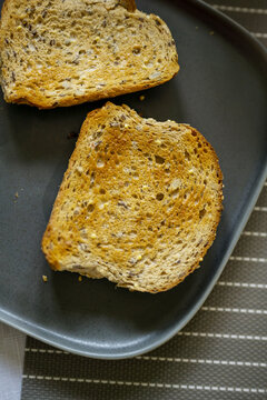 Whole grain seeded toast slices on dark plate, healthy breakfast food concept