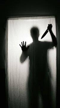 Scary Silhouette of a Killer with a Knife Behind a White Curtain - Horror and Thriller Concept for Crime and Fear