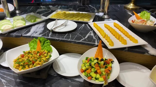 Fresh salad and fruit slice appetizer displayed at hotel buffet counter - panning shot.