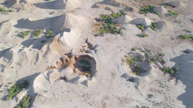 Aerial View of Deep Round Opal Mine Shaft Surrounded by Sandy Excavation Mounds, Coober Pedy, Australia