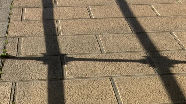 Pattern of rectangular paving stones with metal fence shadows close up overhead