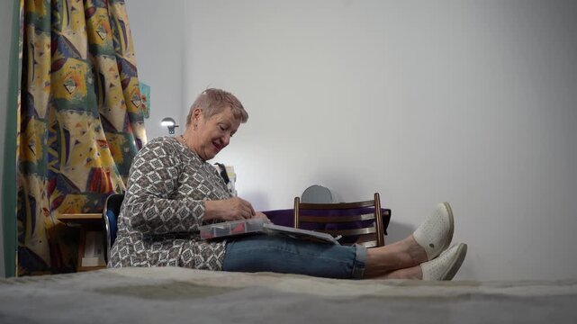 An elderly woman arranges scraps in a craft box and talks.