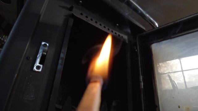 Close up of striking a match on matchbox and lighting a wood stove