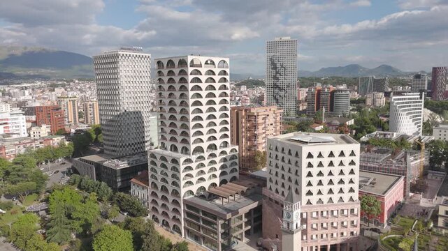 Aerial - Tirana Albania city center with modern high rise towers, clock tower and mountain backdrop