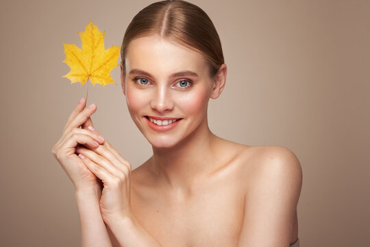 Portrait of beautiful young woman with autumn leafs. Healthy clean fresh skin natural make up beauty eyes