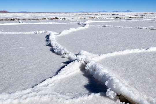 View of the Uyuni Salt Flat featuring intricate hexagonal salt crust patterns under a clear blue sky in Bolivia.