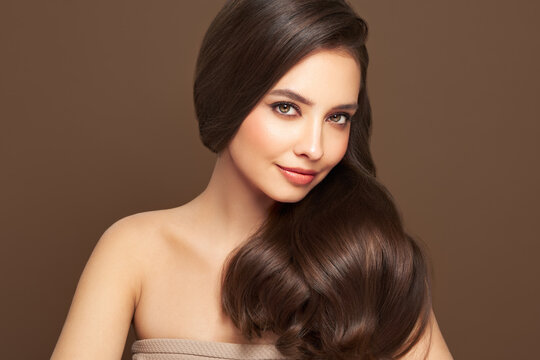 Brunette girl with perfect makeup. Smiling beautiful model woman with long curly hairstyle. Care and beauty hair products