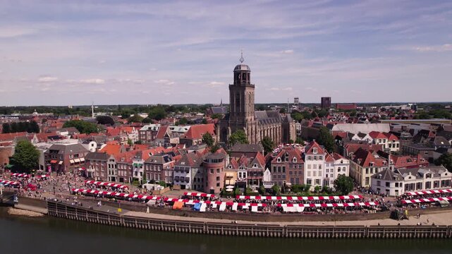 Lebuinus church tower rising above the Hanseatic town descending movement revealing street level market below along boulevard and historic city
