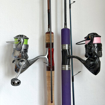 Fishing reels with green and pink line mounted on rods against white background.