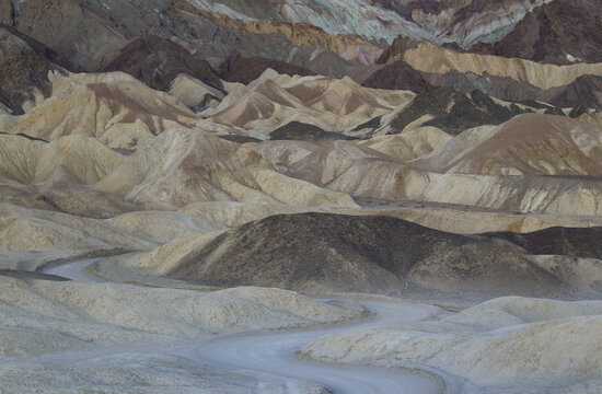 View of the winding dirt road through the colorful badlands and eroded hills of Twenty Mule Team Canyon in Death Valley, California, United States.