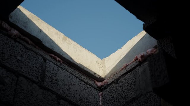 Sky visible through roof opening in unfinished concrete block building